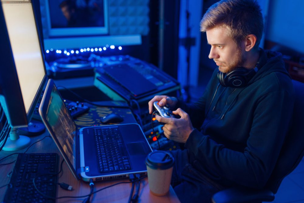 Male gamer in headphones holds joystick and playing videogame on console